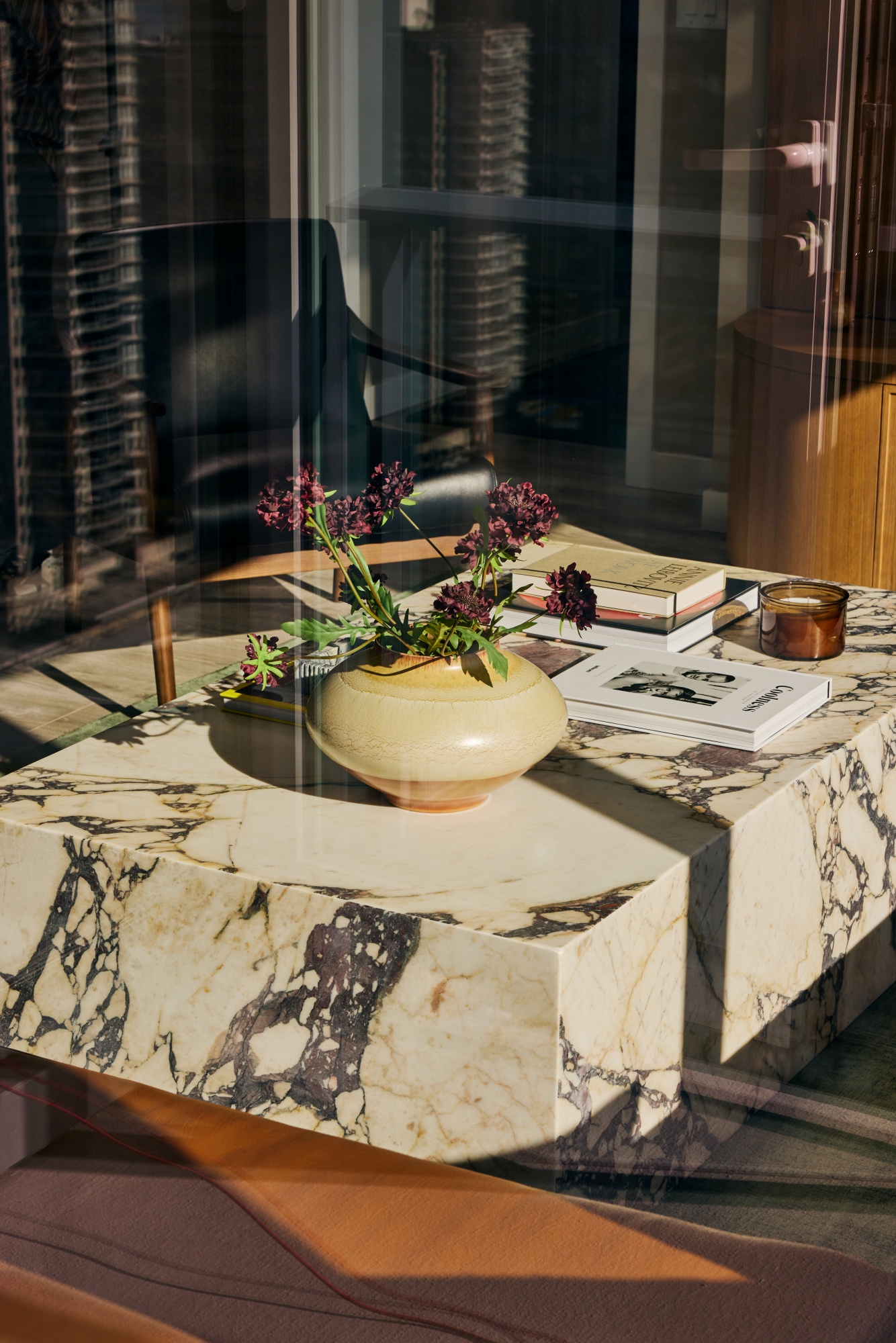 A photo taken through the glass in to a living room looking at a marble coffee table.