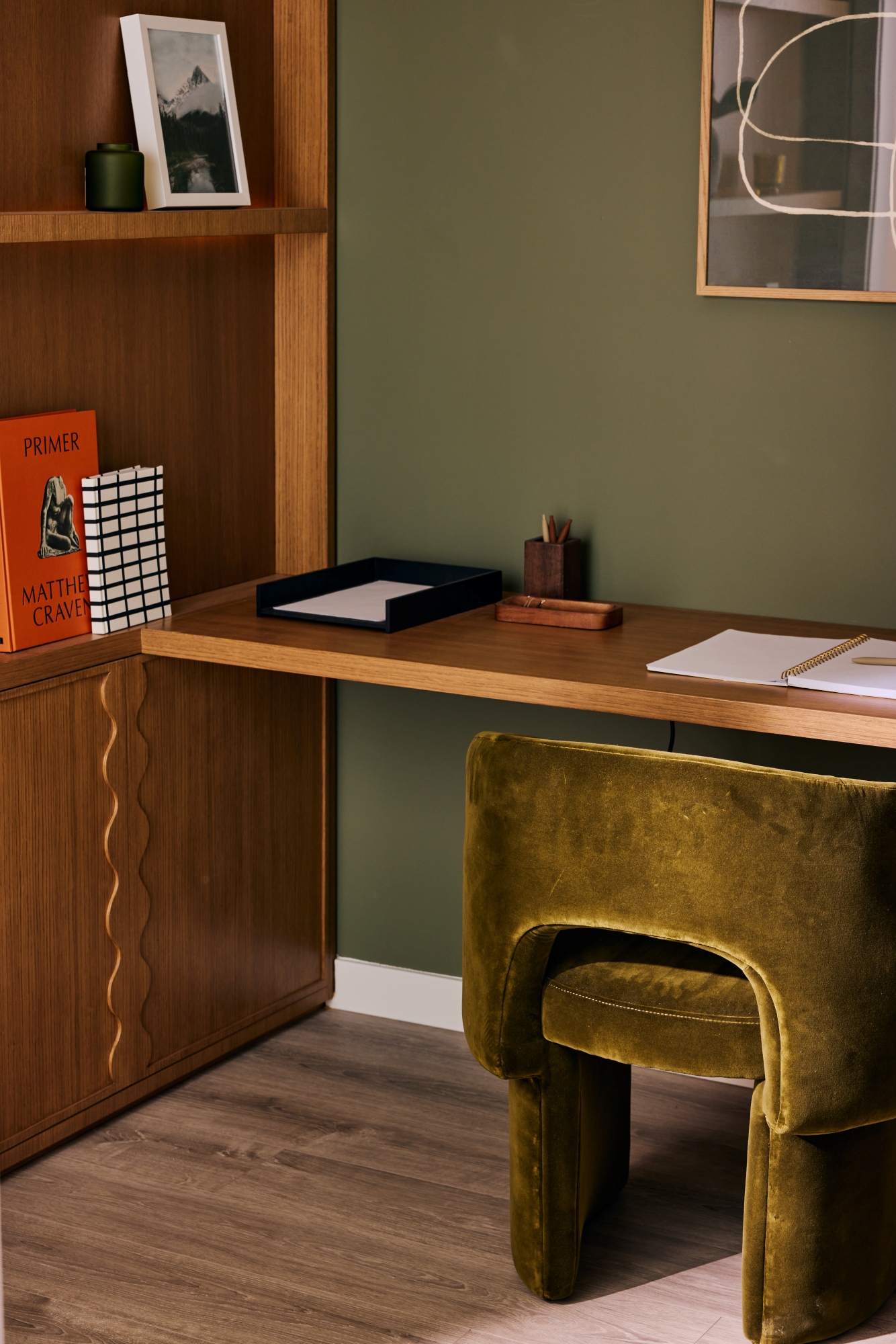 Custom desk and millwork in an office with a velvet green side chair.