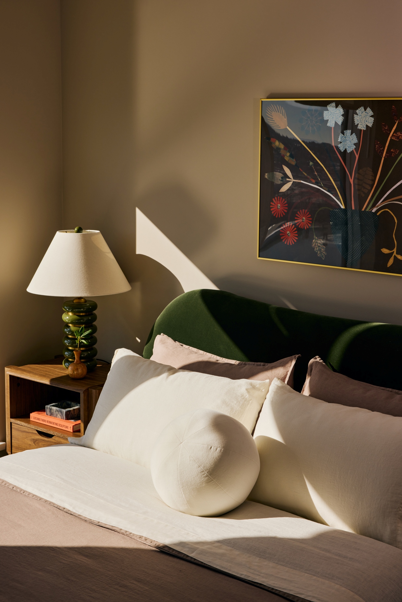 Dark velvet bed with a bold green lamp. Anthropologie art framed over the bed.